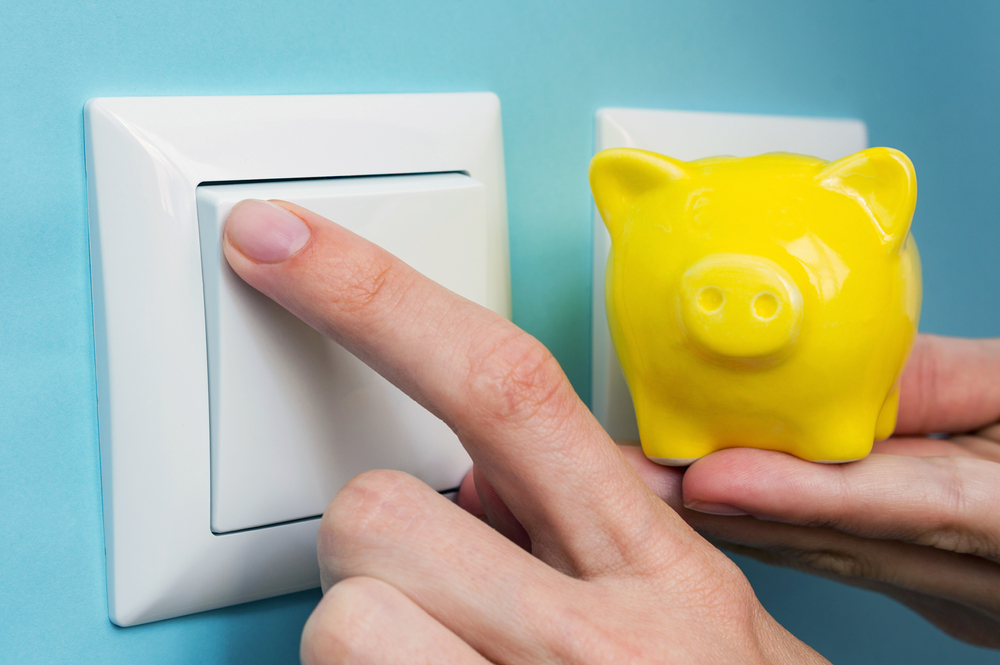 Hand,With,Yellow,Piggy,Bank,Turns,Off,Electric,Lights,At